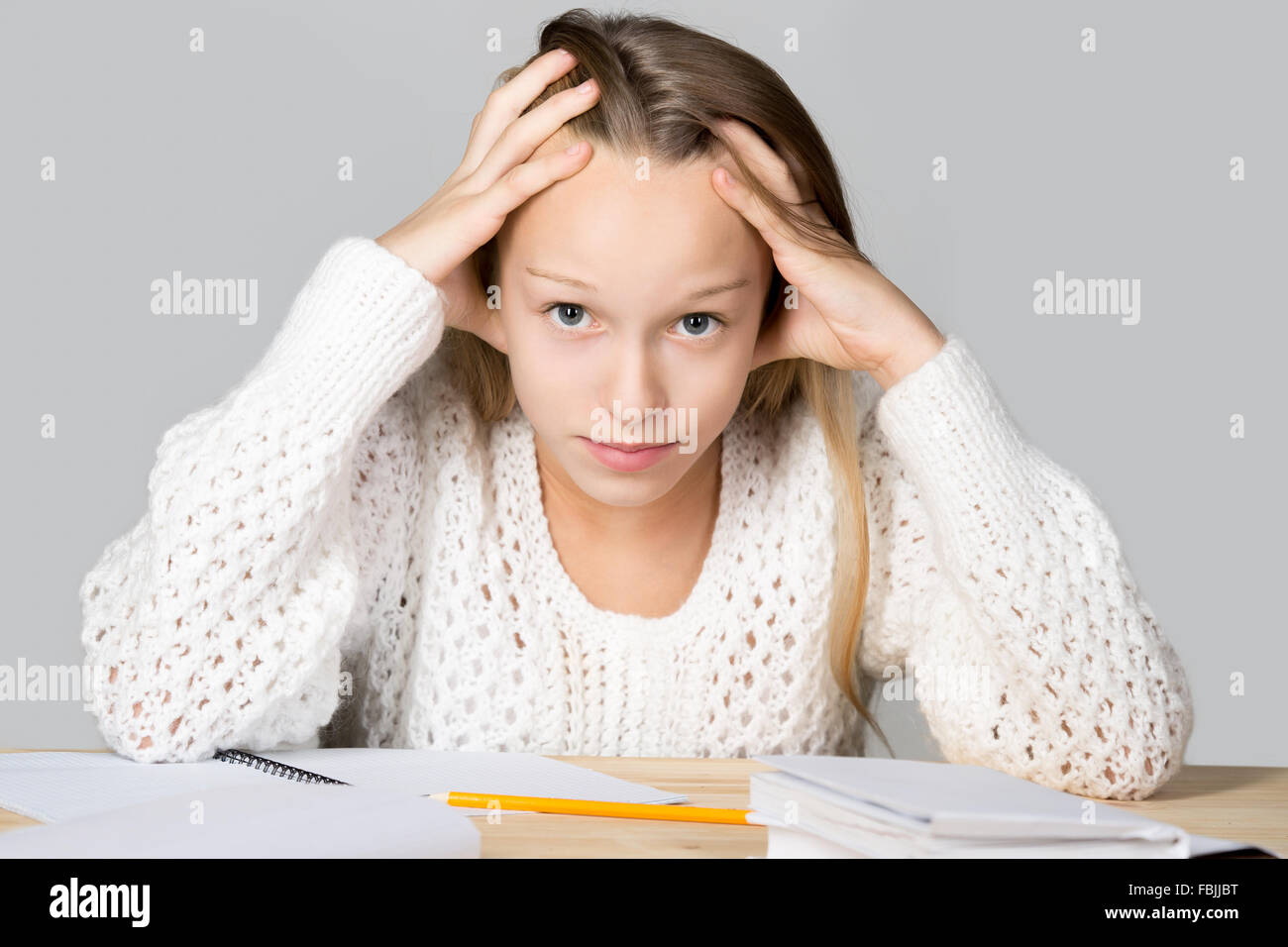 Portrait of unhappy beautiful casual girl, sitting at desk, holding her head in arms with overwhelmed frustrated expression Stock Photo