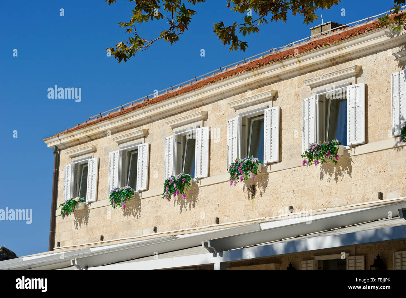 Opened wooden shutters and window flower decorations at a hotel in Dubrovnik, Croatia. Stock Photo