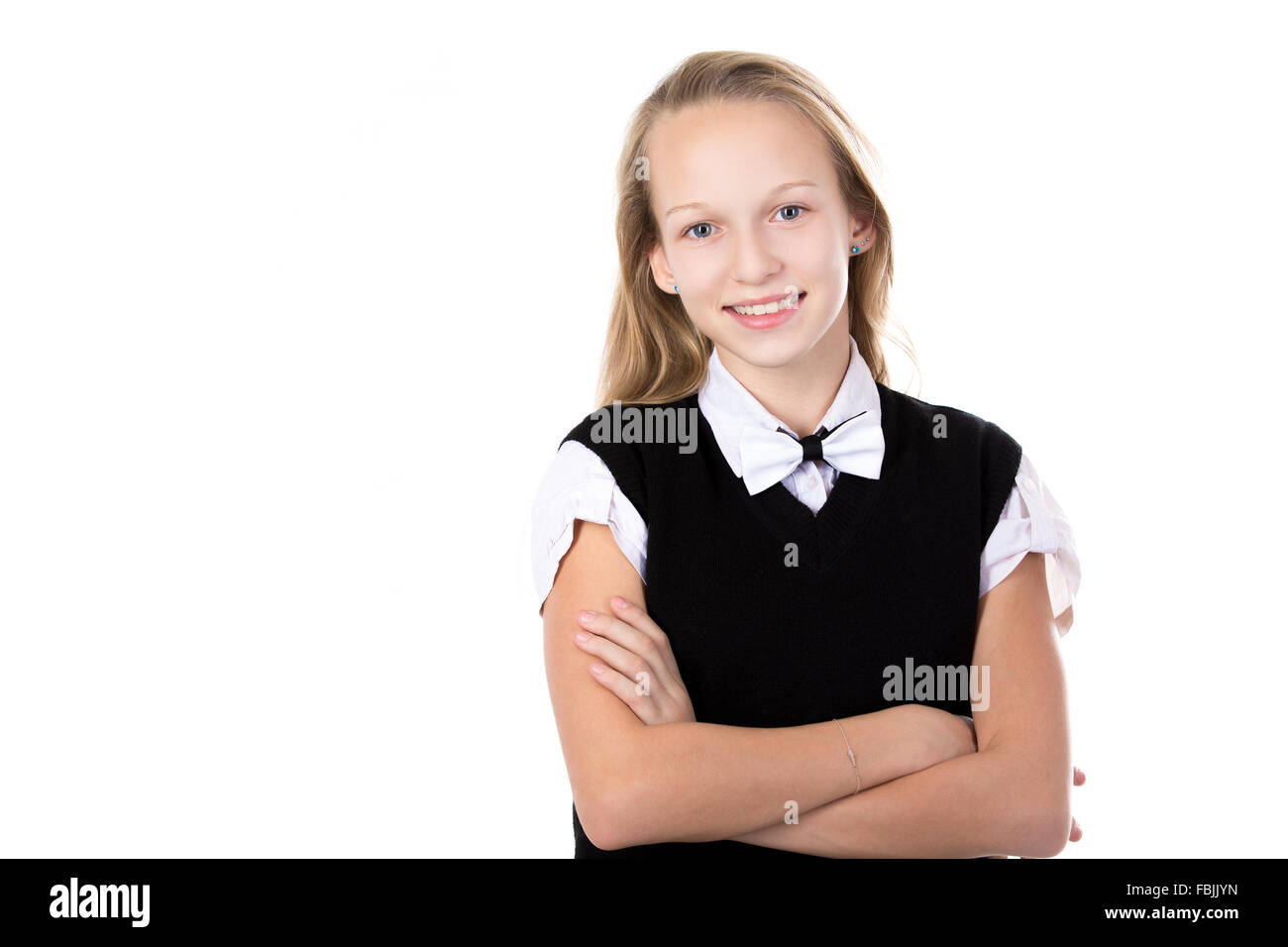 Portrait of happy cute beautiful blond schoolgirl wearing black and white formal outfit and bow tie, holding arms folded Stock Photo