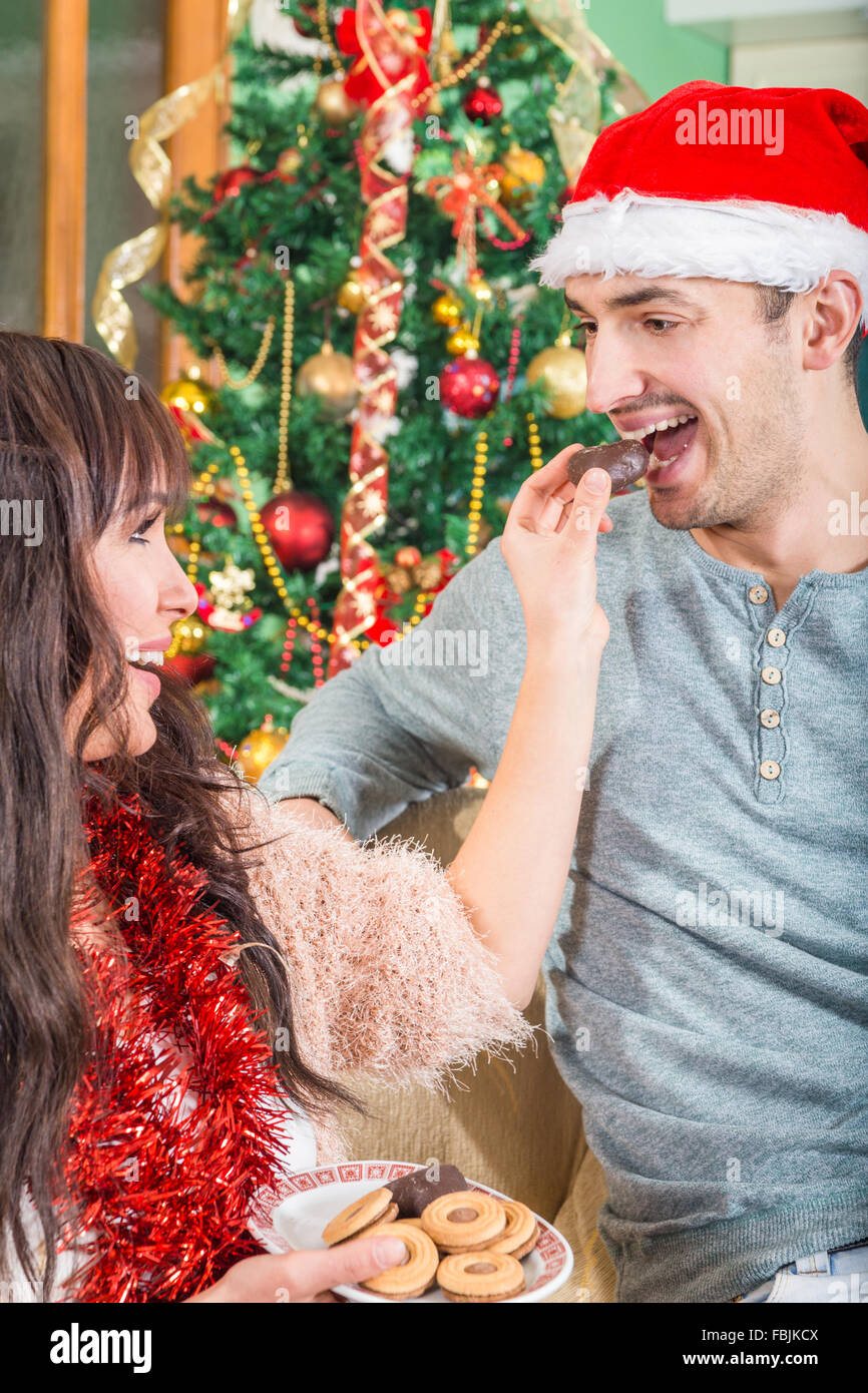 Woman Feeding a Man With Sweet Cookies or Cake from a Plate. Love and New Year`s with Young Couple. New Year and Romantic Chemis Stock Photo