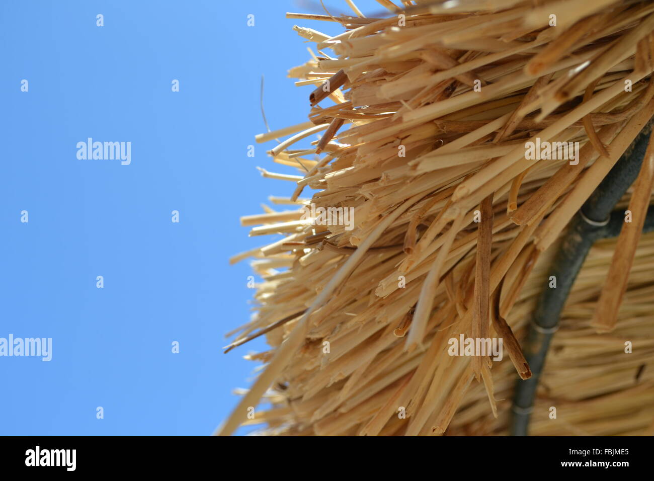 Straw umbrella parasol edge with clear blue sky behind on a sunny day in Spain Stock Photo