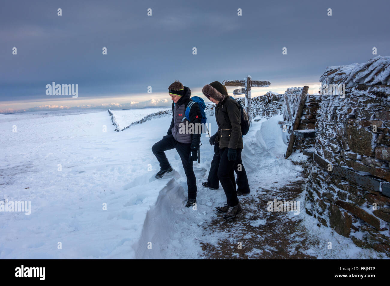 Pen-y-ghent in winter with three walkers leaving the summit wall, Yorkshire Dales. Stock Photo