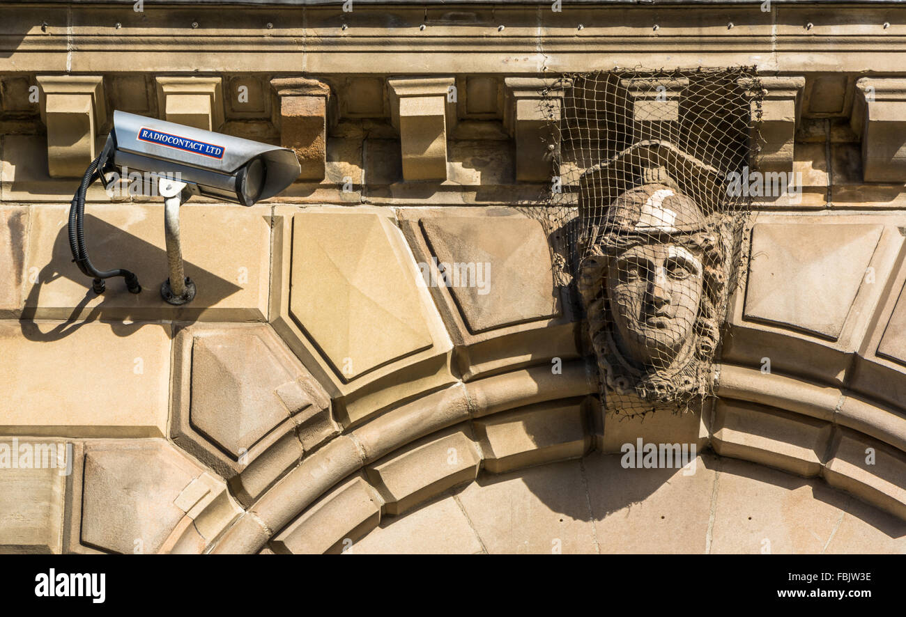 CCTV camera points to face of a statue on Belfast's custom house. Stock Photo