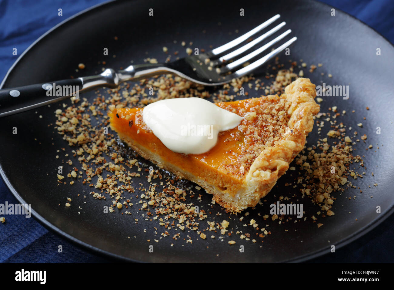 piece pumpkin pie with cream on black plate Stock Photo
