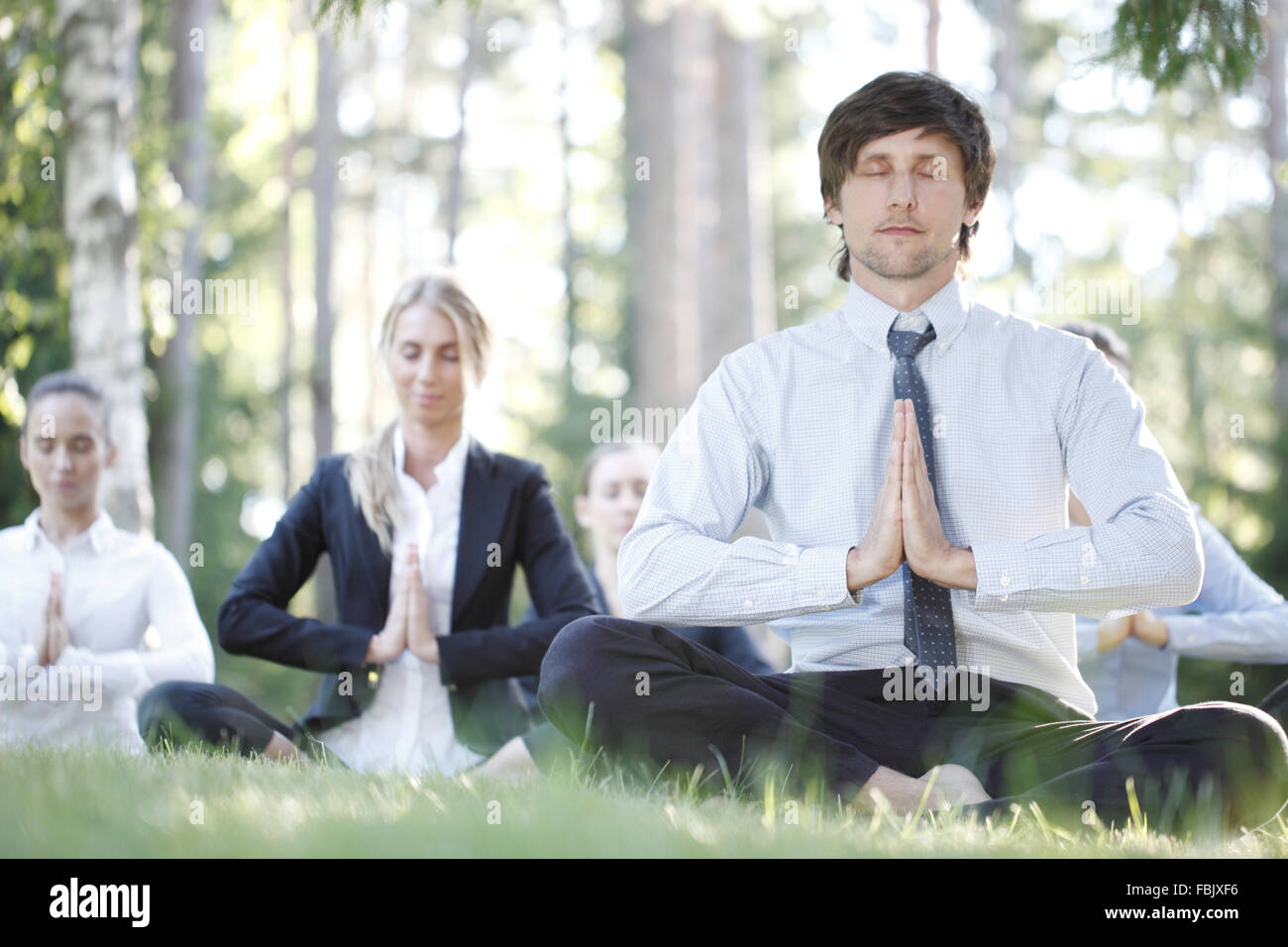Business people practicing yoga in park Stock Photo - Alamy