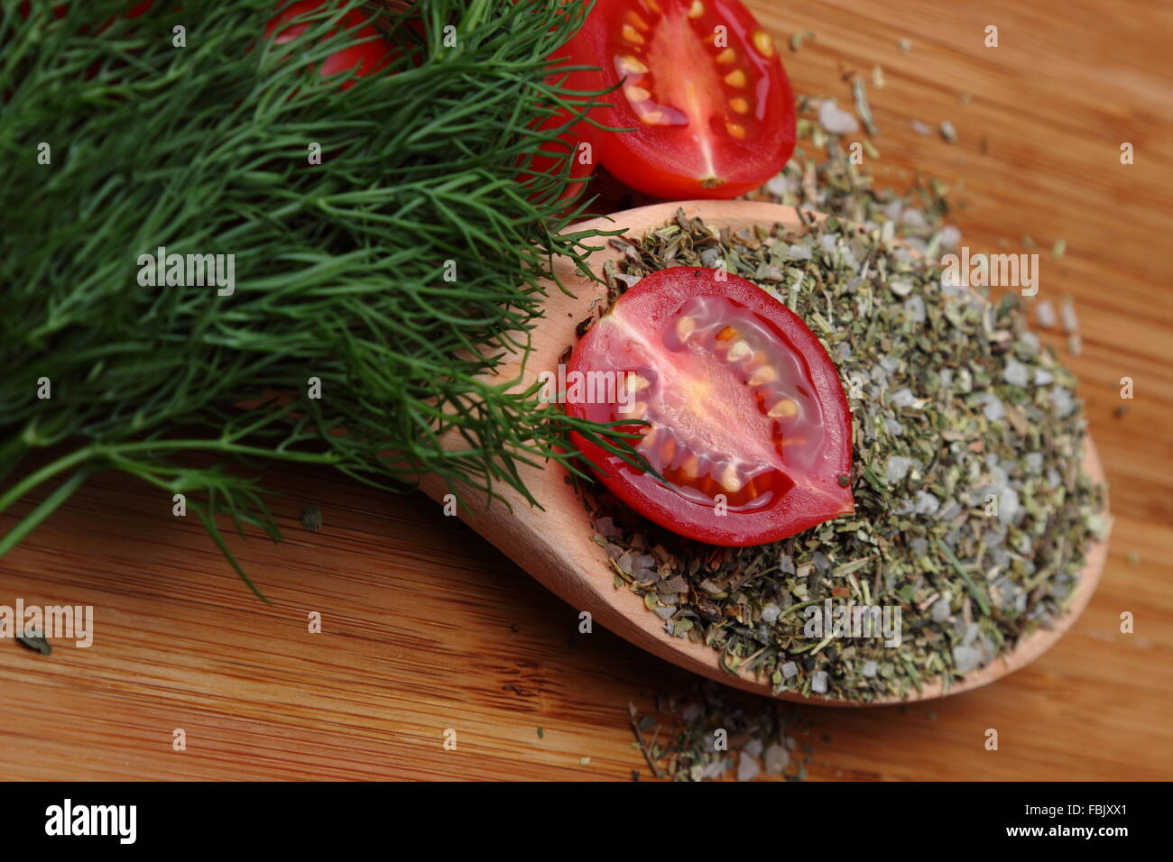 Tomatoes, dill and spices on a wooden spoon Stock Photo