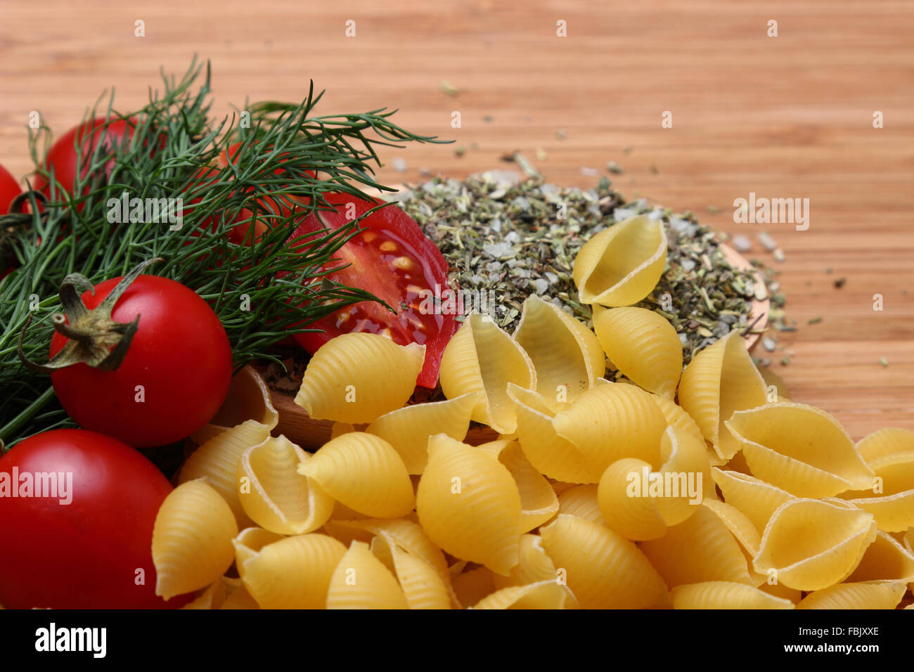 Pasta, tomatoes and spices on wooden table background Stock Photo