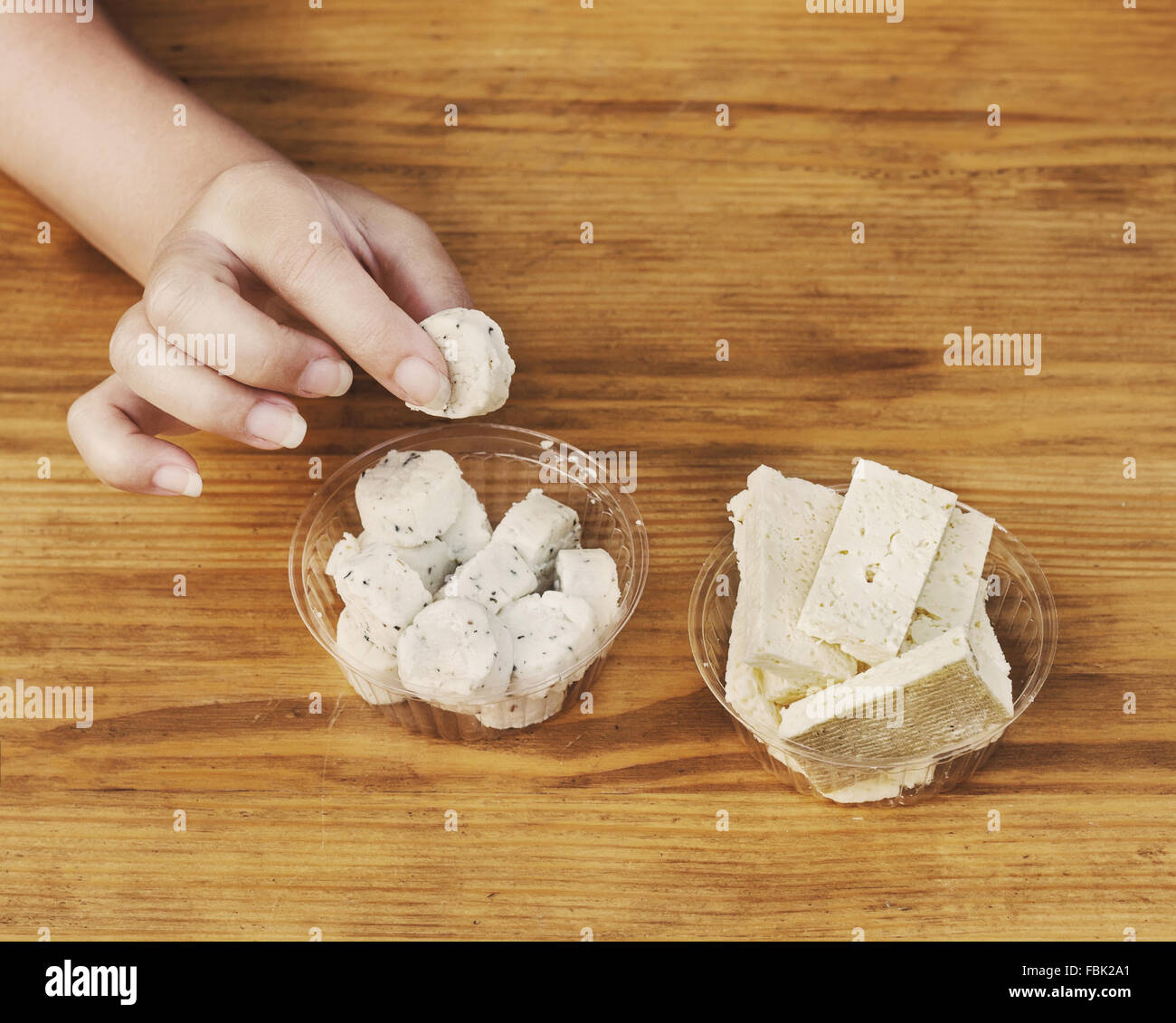 Girl take in hand a slice of sheep cheese with potherbs Stock Photo