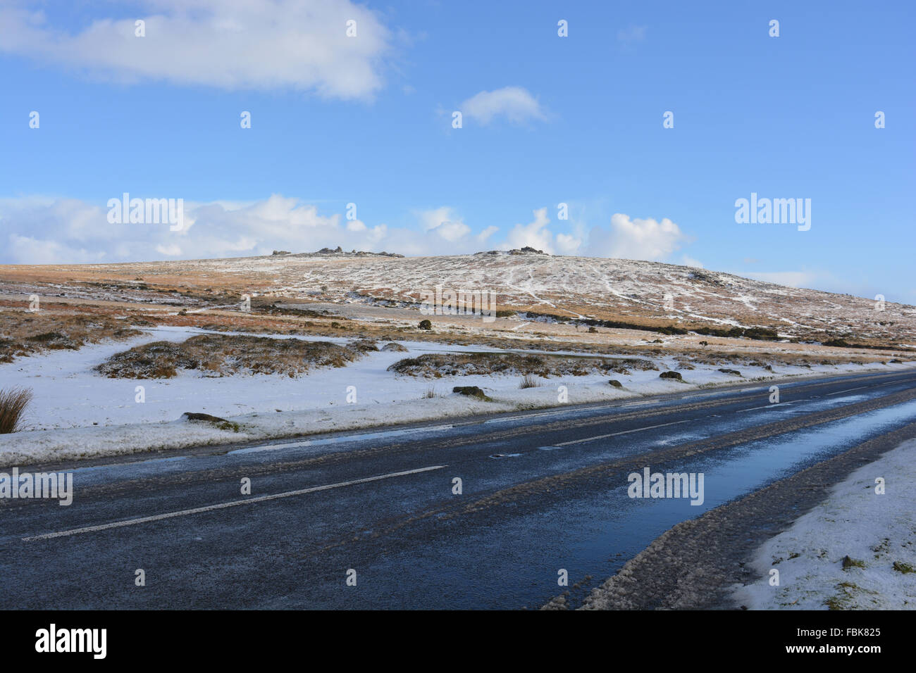 Pork Hill in winter with melting snow and ice on road, Great Staple Tor  on horizon, Dartmoor National Park, Devon, UK Stock Photo