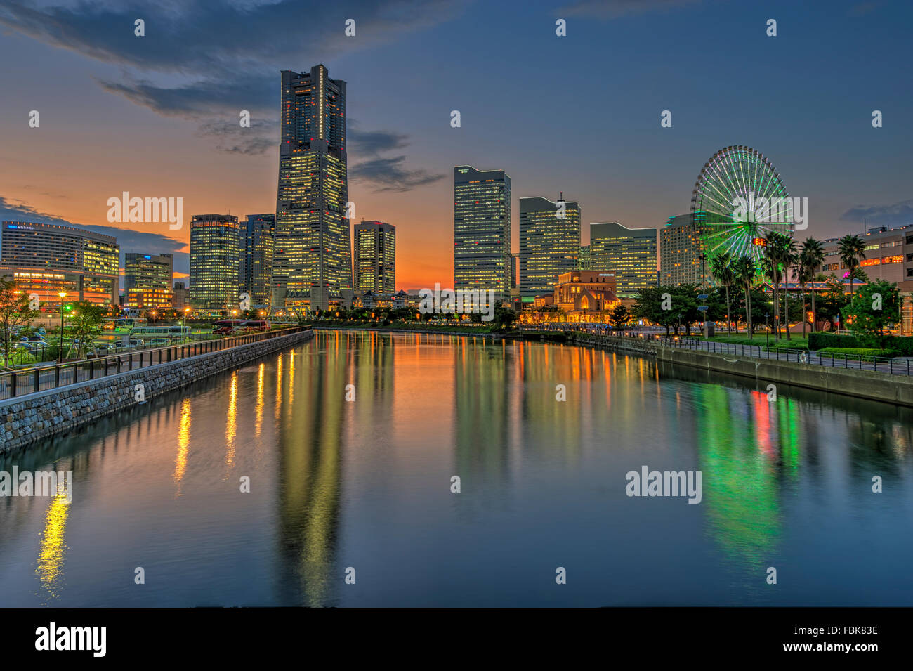 The reflection of Yokohama Landmark Tower and the surrounding modern office buildings on water during twilight Stock Photo