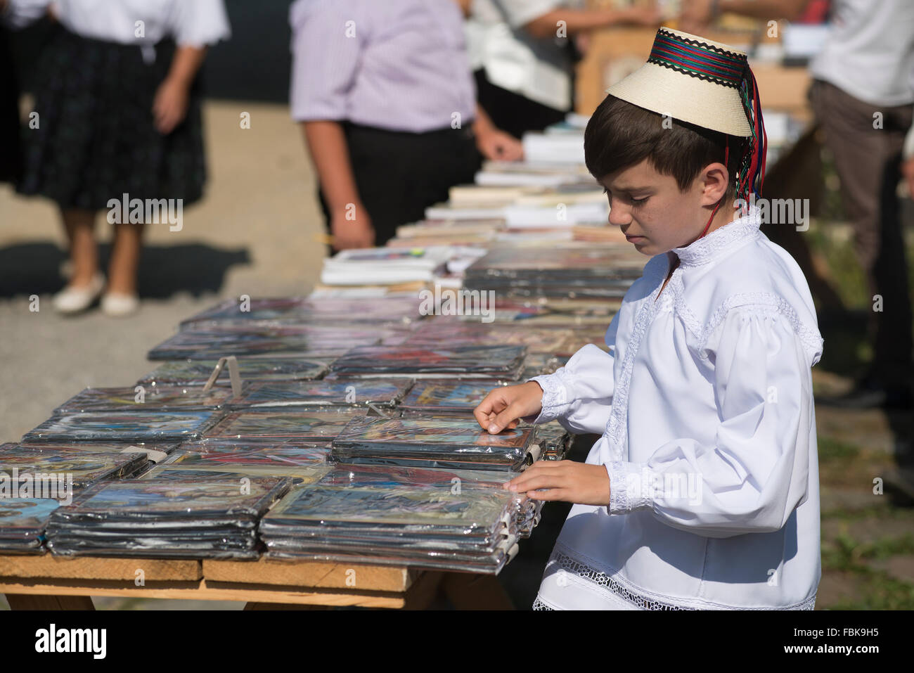 boy in traditional costume sells religious objects outdoors in the