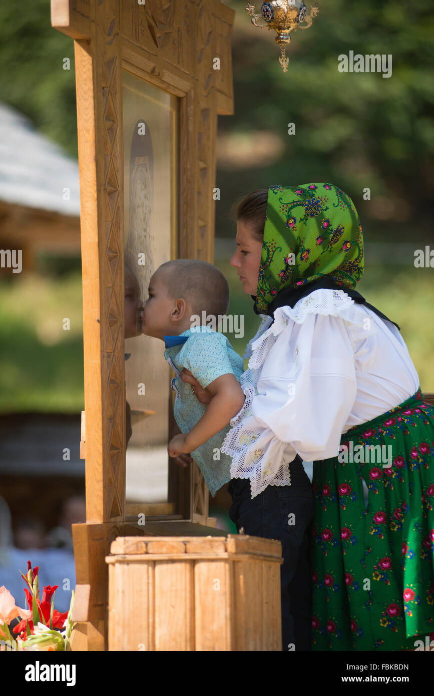 mother with the baby while kissing a religious icon in the district of Maramures, Romania Stock Photo