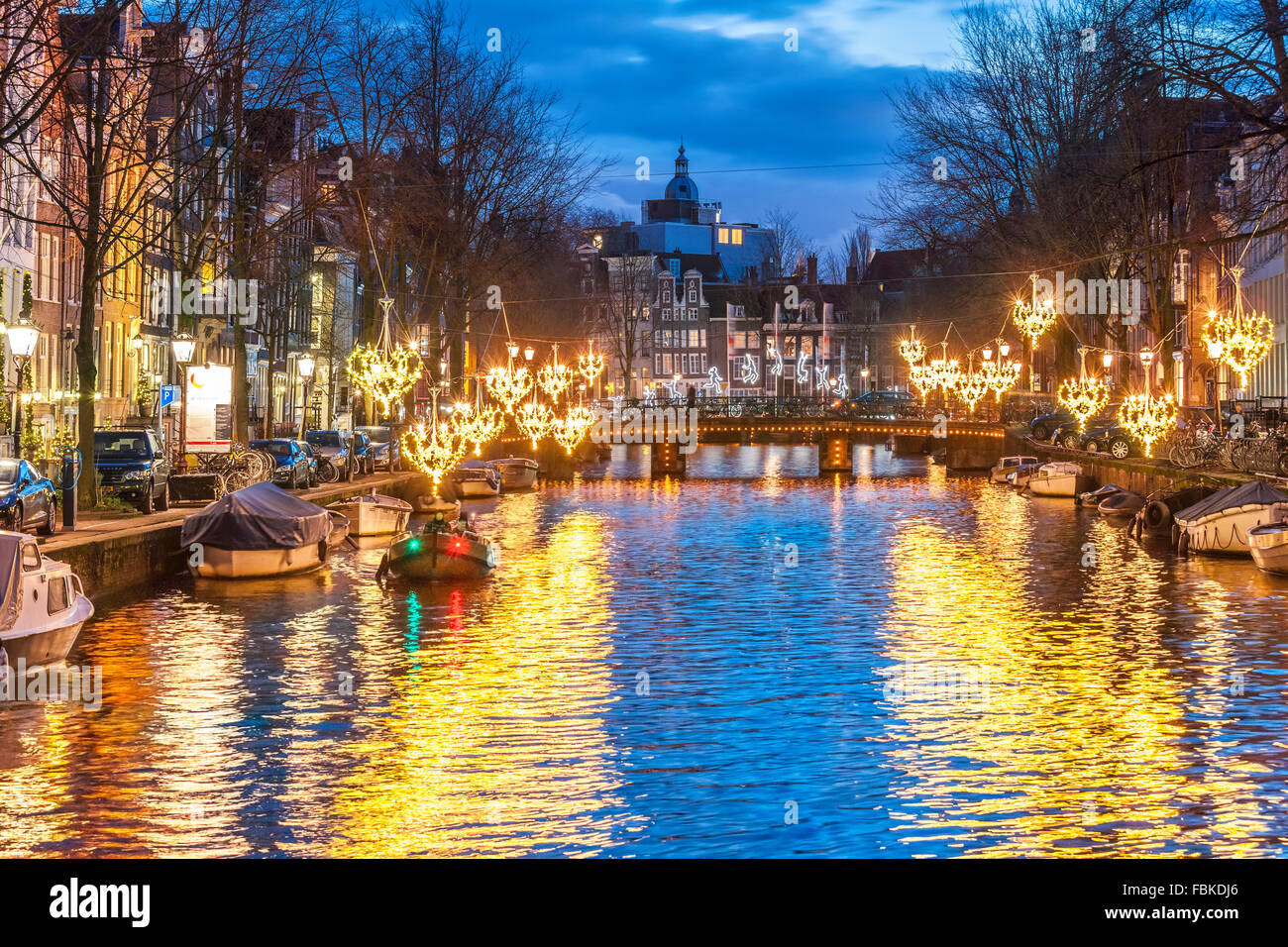 Amsterdam Herengracht Canal in winter with seasonal lights and small boat at dusk. Amsterdam Light Festival Stock Photo