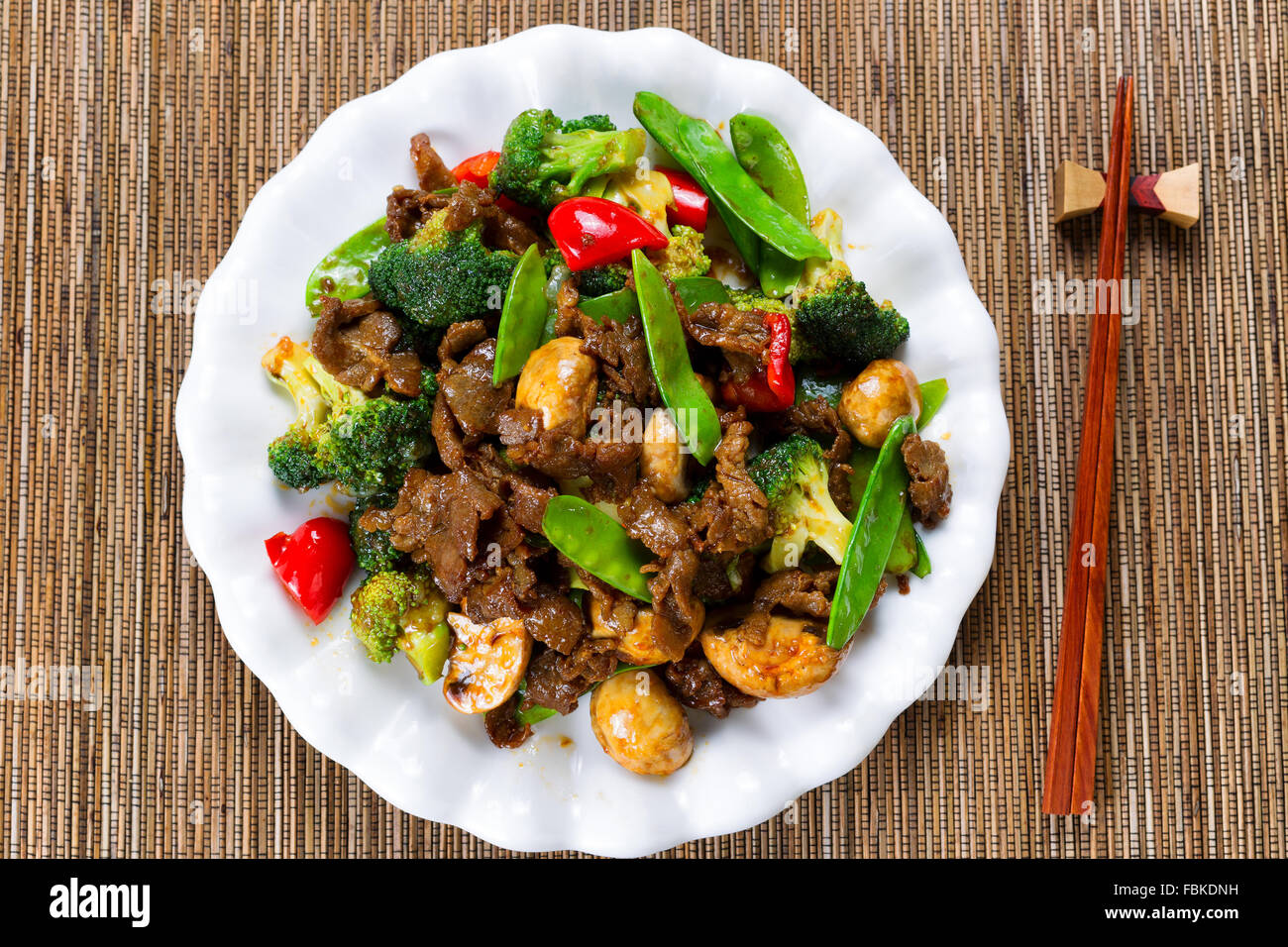 High angle view of tender beef slices, mushrooms, broccoli, peppers and peas in white plate. Stock Photo