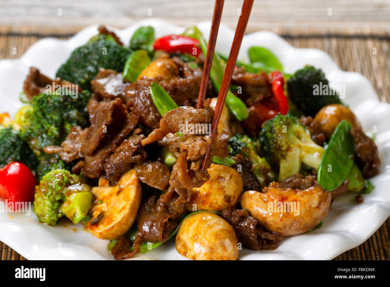 Close up view of tender beef slices, mushrooms, broccoli, peppers and peas in white plate. Stock Photo