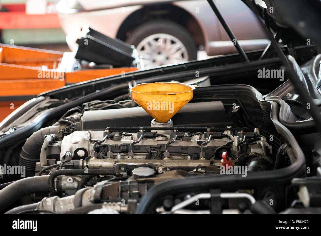 Yellow plastic funnel for pouring oil placed in the sump of a car