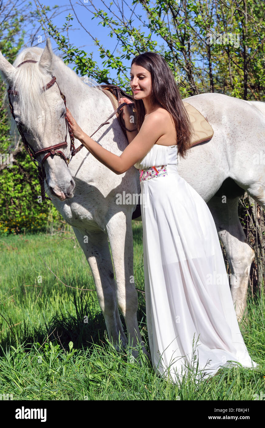 Young attractive woman in white dress with white horse Stock Photo