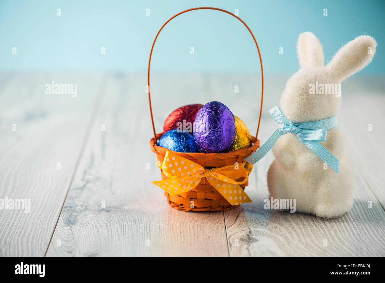Easter eggs in a basket with a bunny on a white table Stock Photo - Alamy