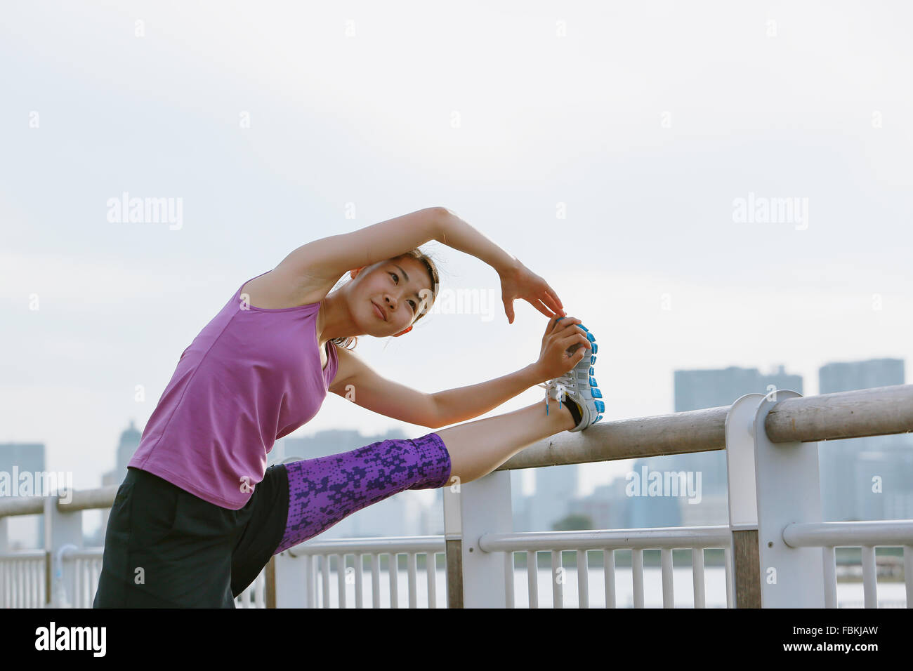 Young Japanese woman stretching before her run downtown Tokyo Stock ...
