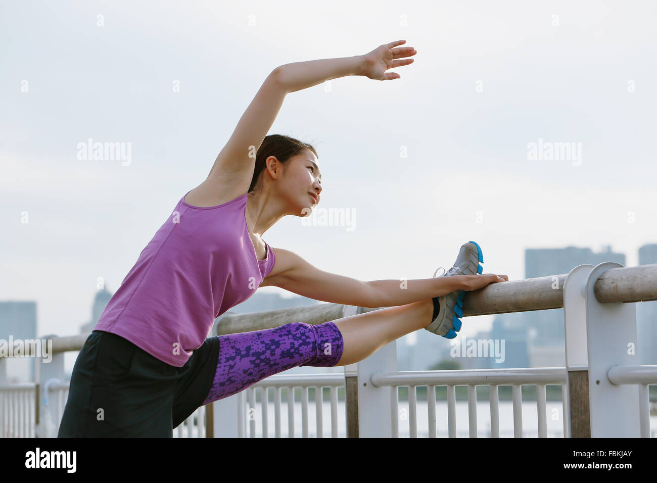 Young Japanese woman stretching before her run downtown Tokyo Stock