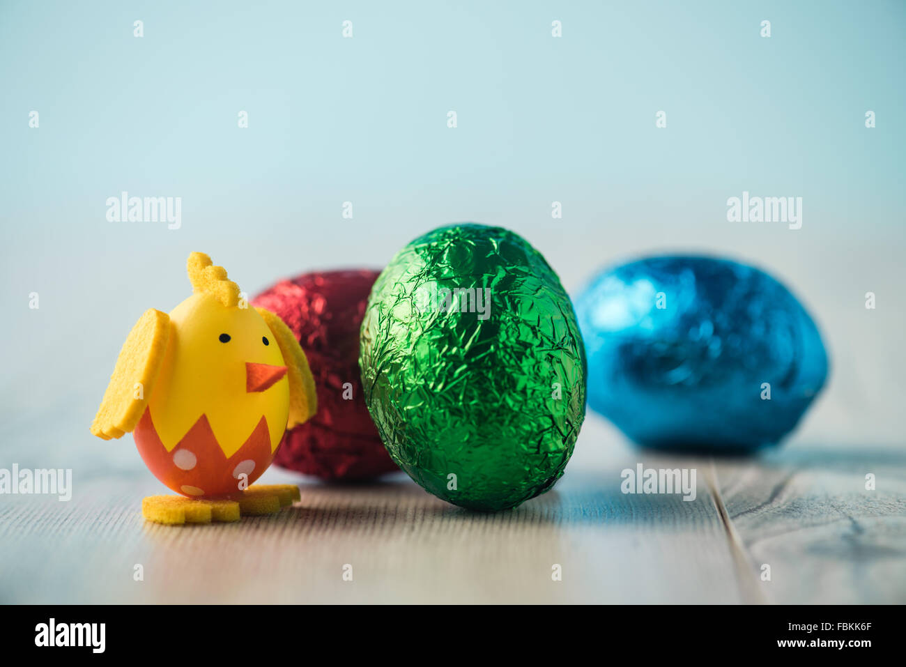 Chicken figurine, red, green and blue easter egg on a white table Stock Photo