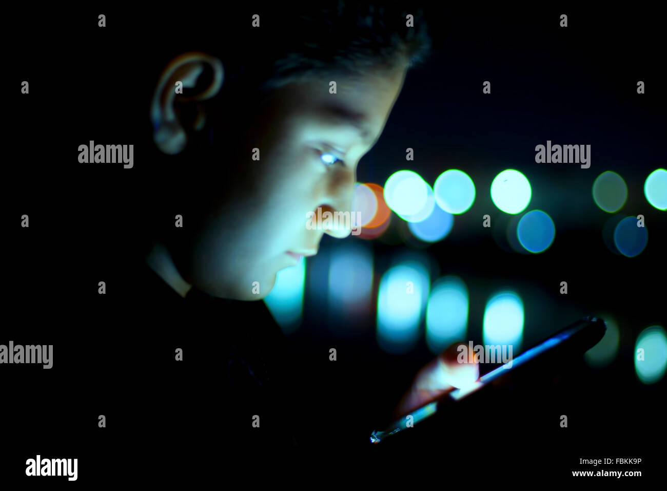 Caucasian Boy busy using cell phone at night in the busy City wearing all black Stock Photo Alamy