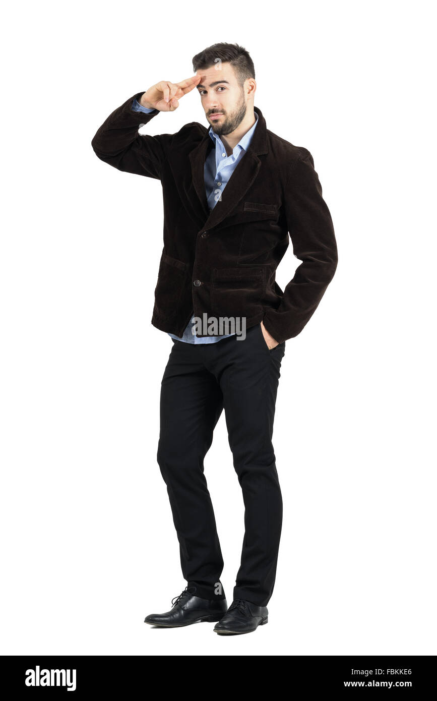 Young bearded man in corduroy coat saluting at camera. Full body length portrait isolated over white studio background. Stock Photo
