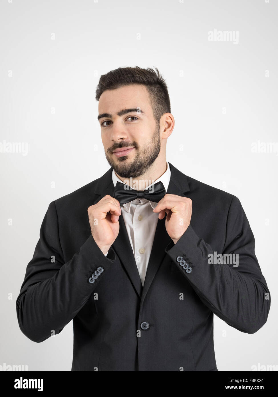 Funny excited groom adjusting his bow tie looking at camera