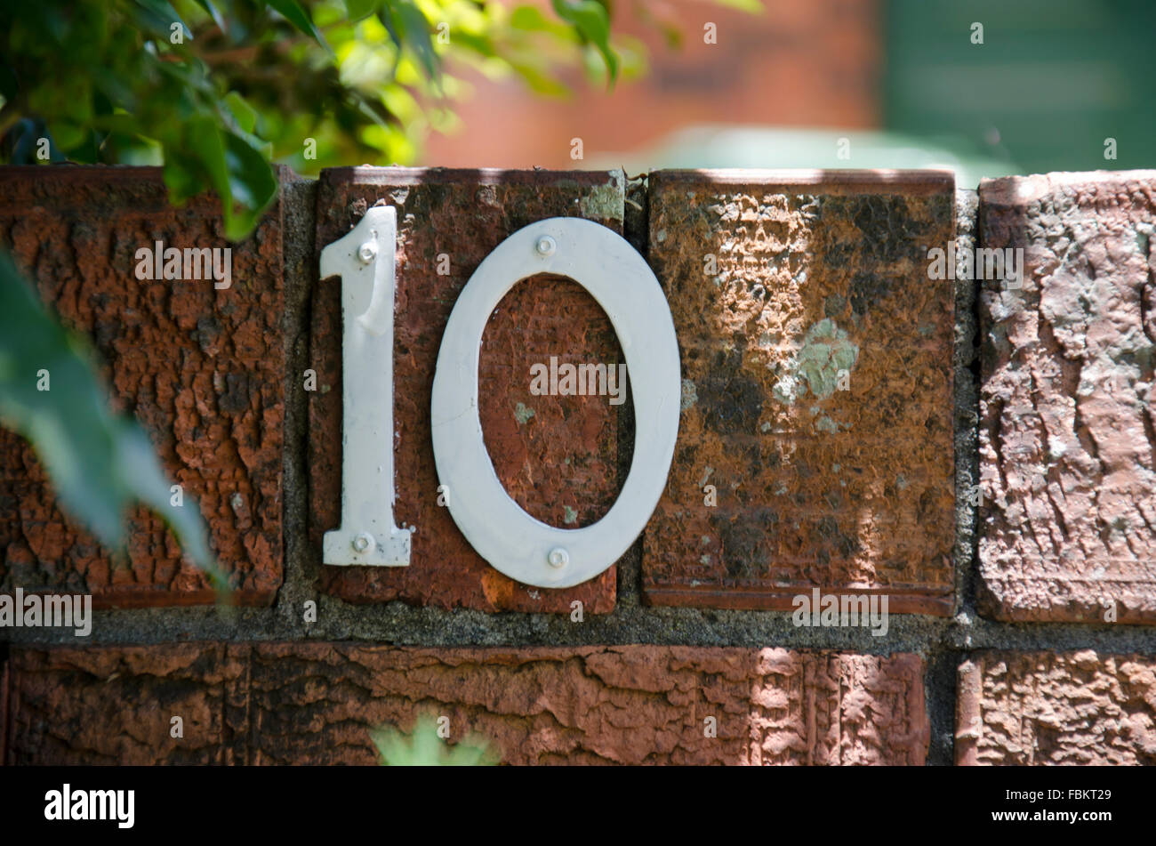 A metal plate house number 10 screwed into a brick wall in Australia Stock Photo
