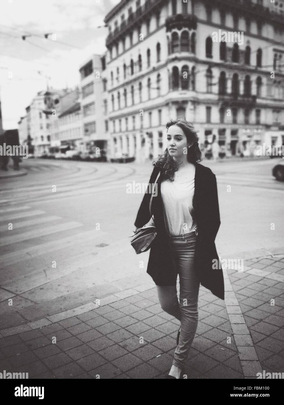 Full Length Of Young Woman Walking On City Street Stock Photo