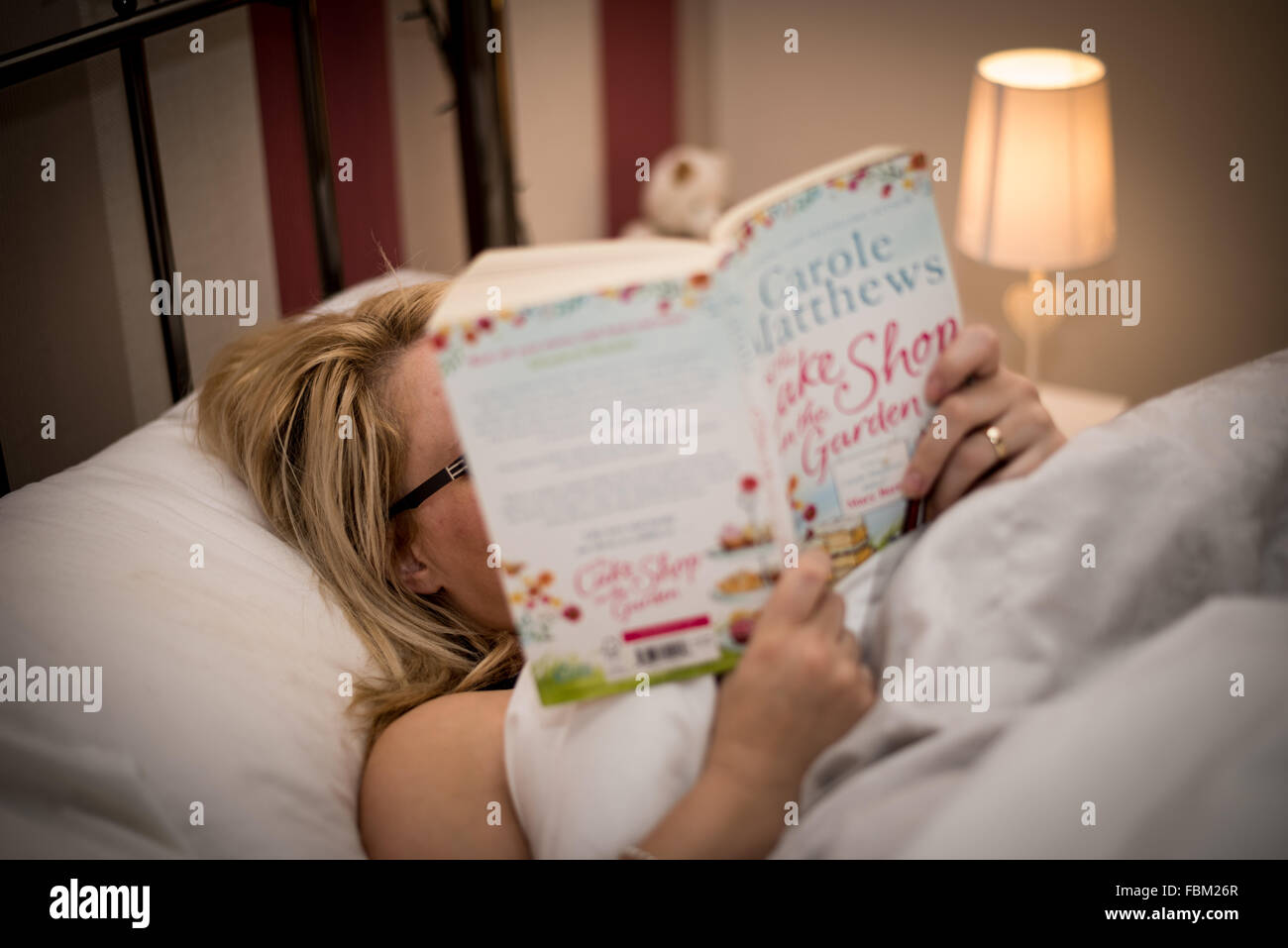 A woman reading a book in bed Stock Photo