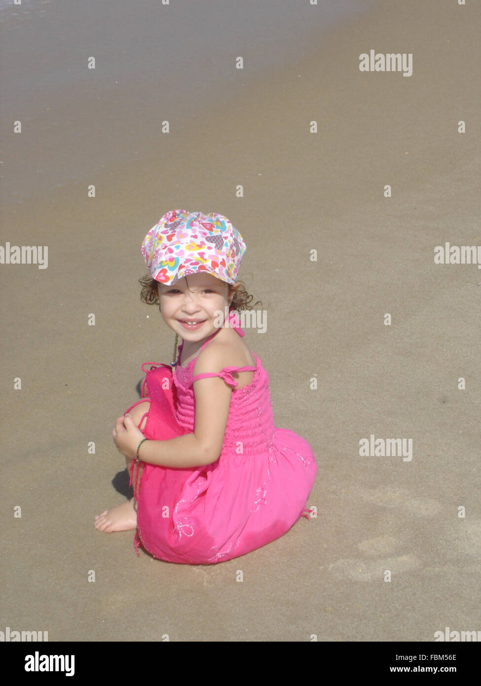 Portrait Of Little Girl Sitting On Sand At Beach Stock Photo - Alamy