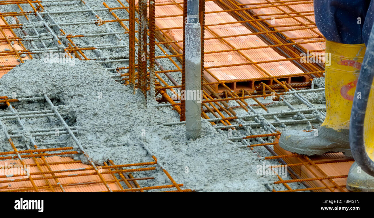 Construction worker compacting liquid cement in reinforcement form work ...