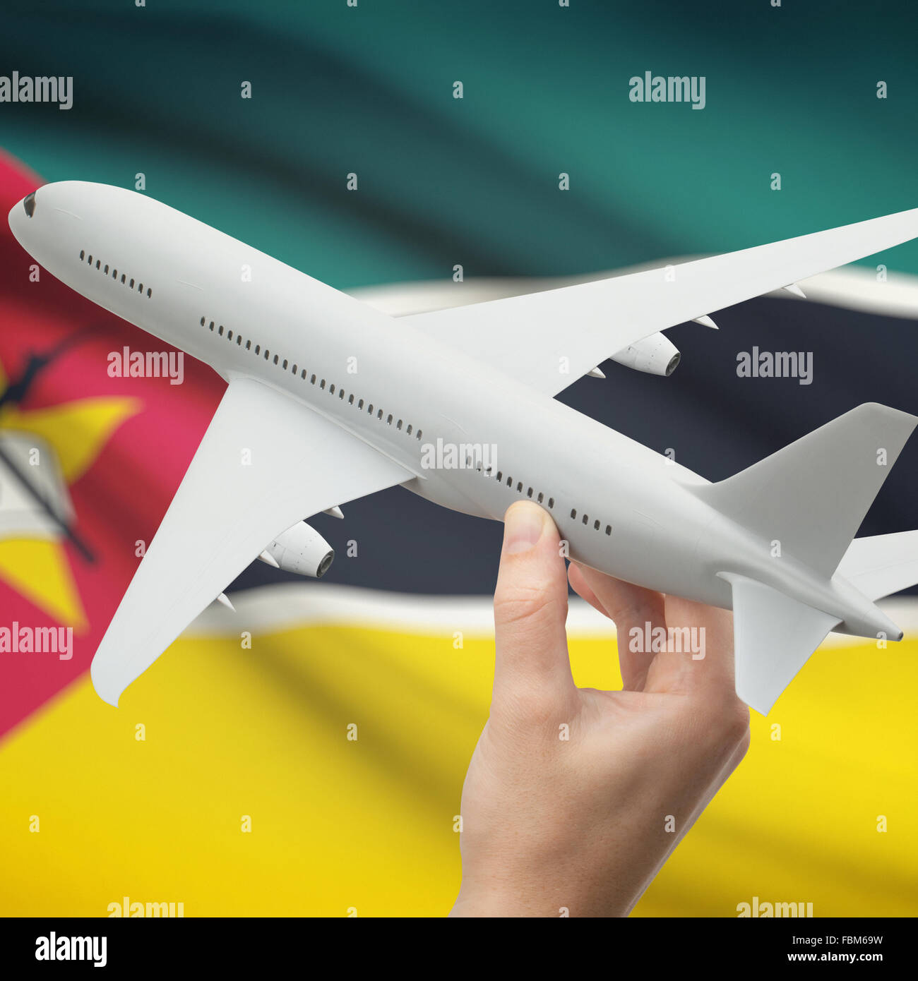 Airplane in hand with national flag on background series - Mozambique Stock Photo