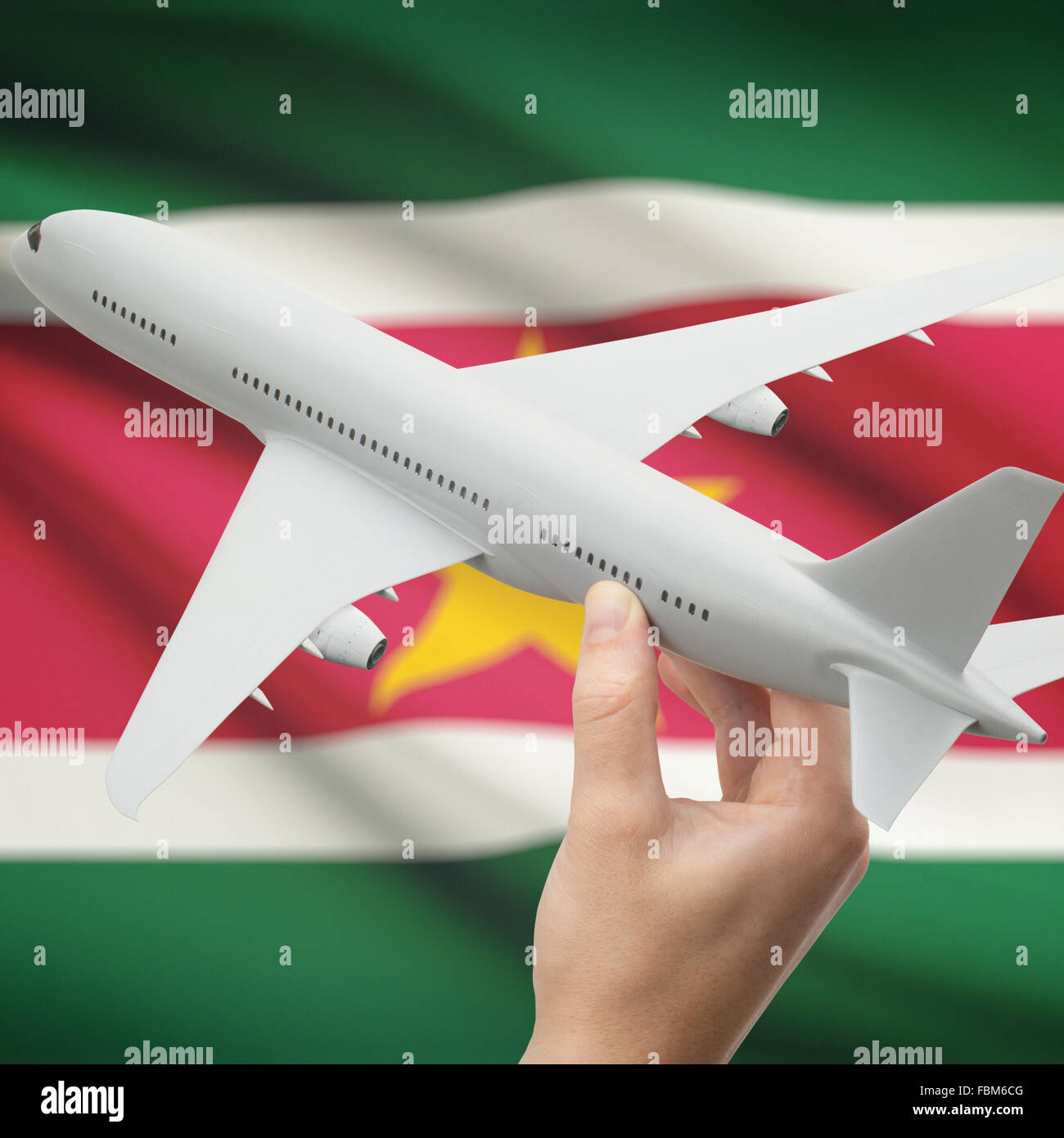 Airplane in hand with national flag on background series - Suriname Stock Photo