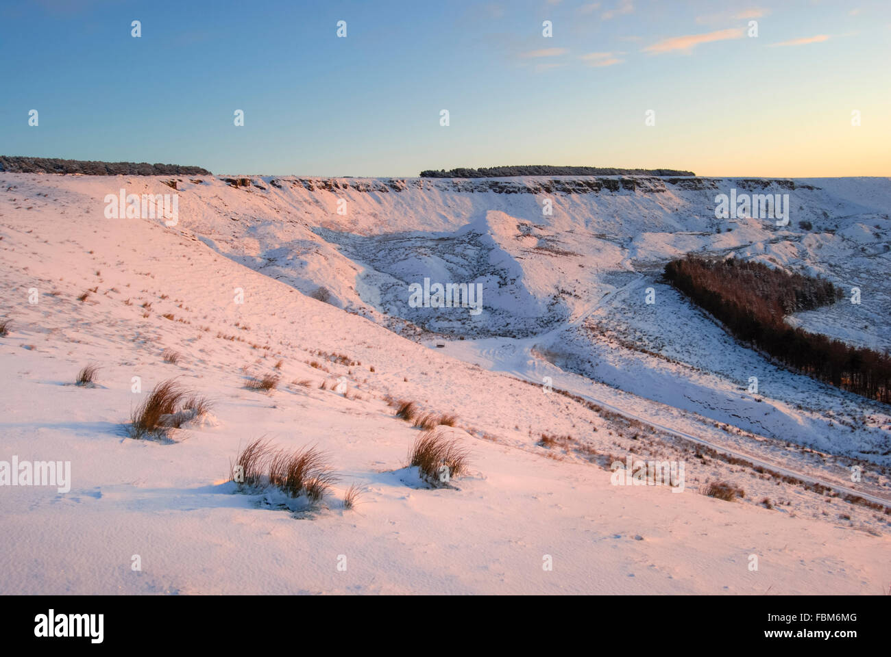 Sunset glow on a snowy landscape above the village of Charlesworth, Derbyshire in Northern England. Stock Photo