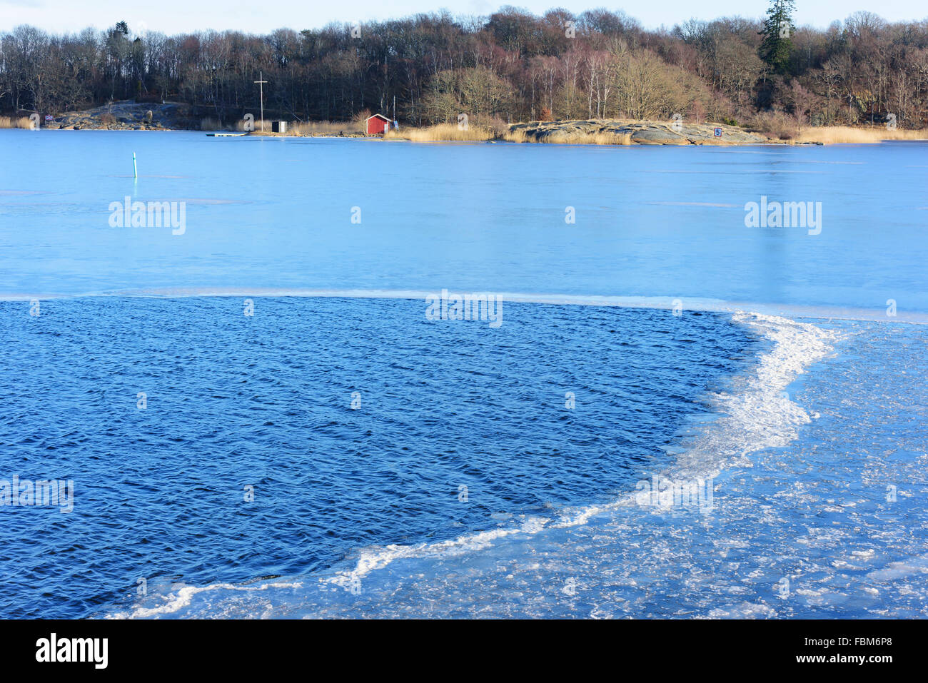 A boundary between calm sea water and ice form a small area of broken ice that almost look like foam. Stock Photo