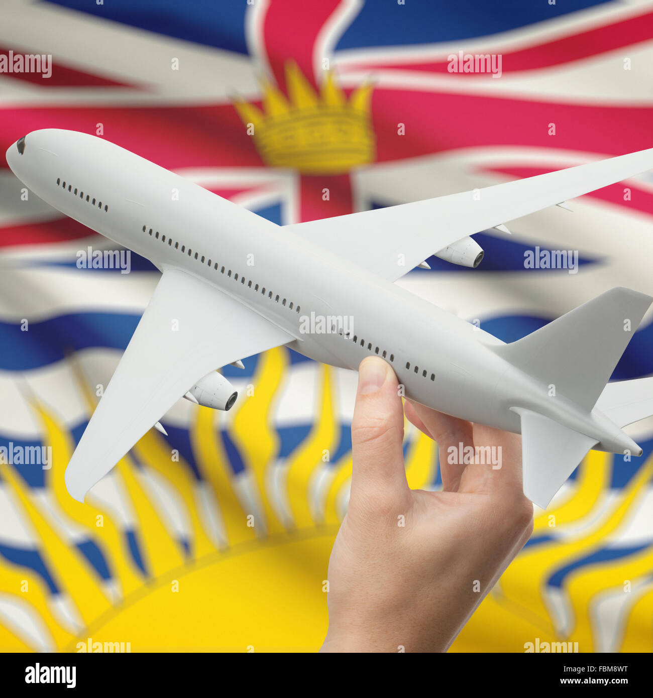 Airplane in hand with Canadian province or territory flag on background series - British Columbia Stock Photo