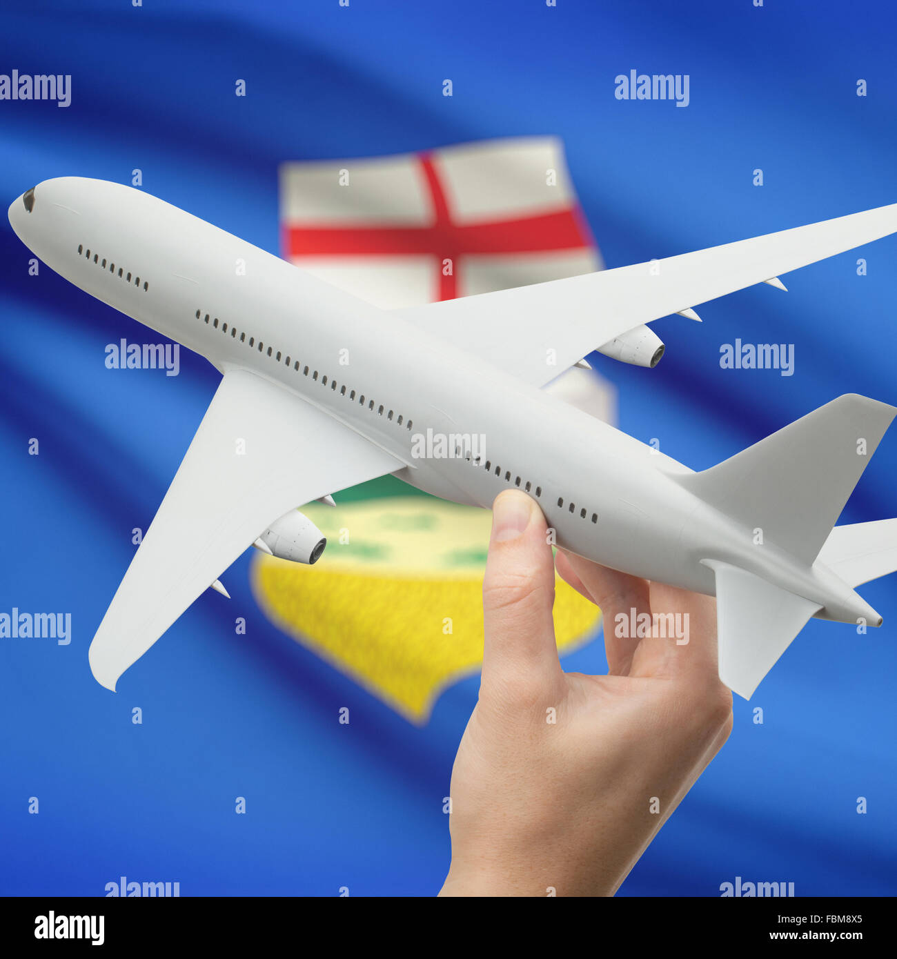 Airplane in hand with Canadian province or territory flag on background series - Alberta Stock Photo