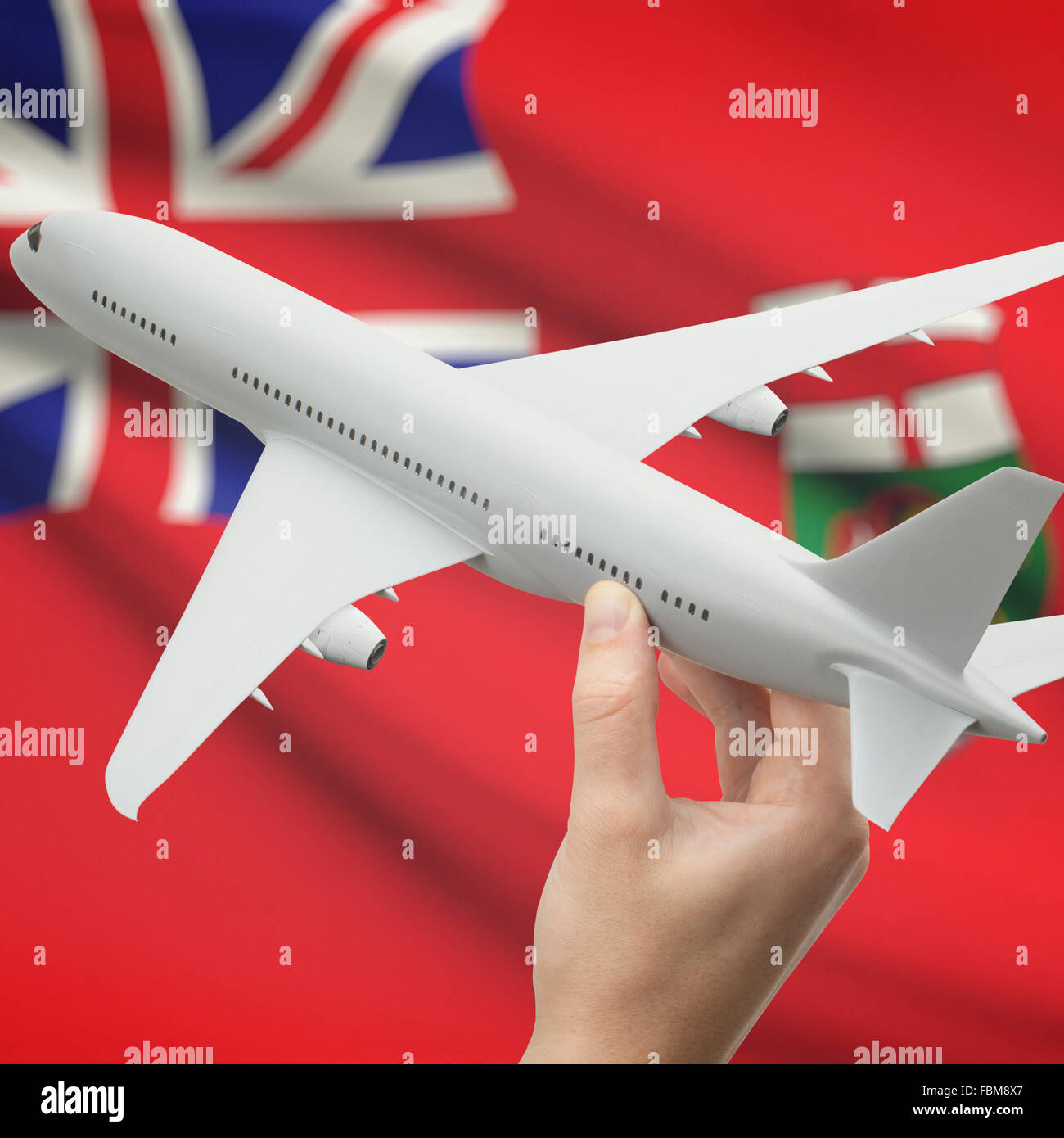 Airplane in hand with Canadian province or territory flag on background series - Manitoba Stock Photo