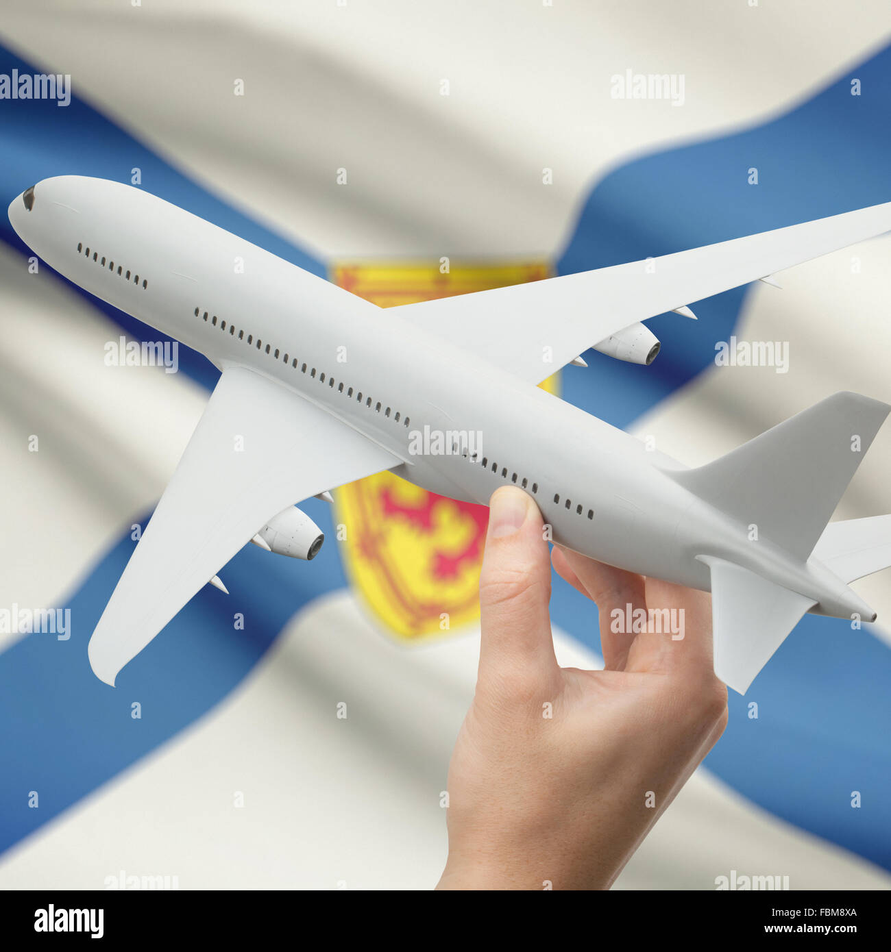 Airplane in hand with Canadian province or territory flag on background series - Nova Scotia Stock Photo