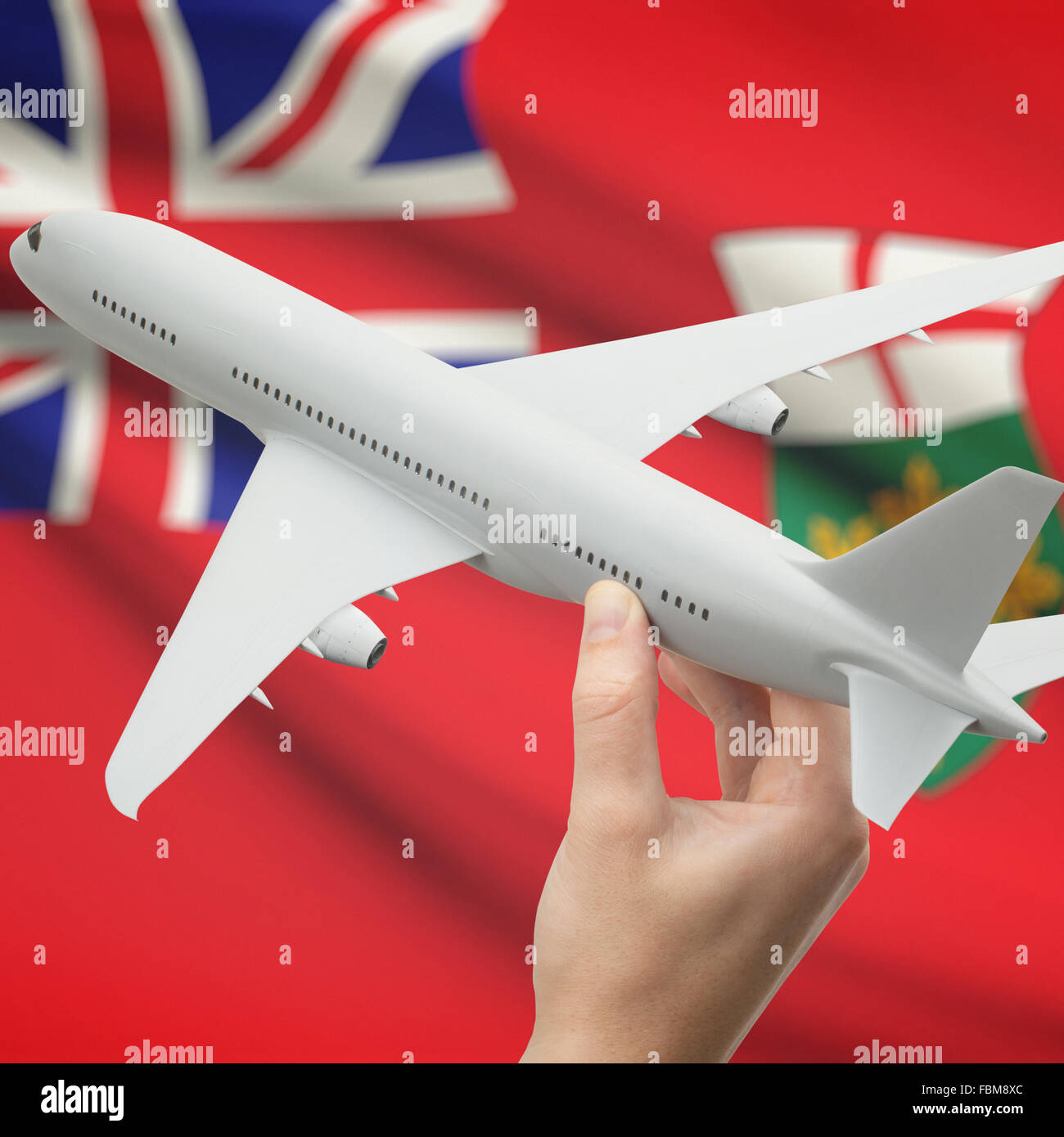 Airplane in hand with Canadian province or territory flag on background