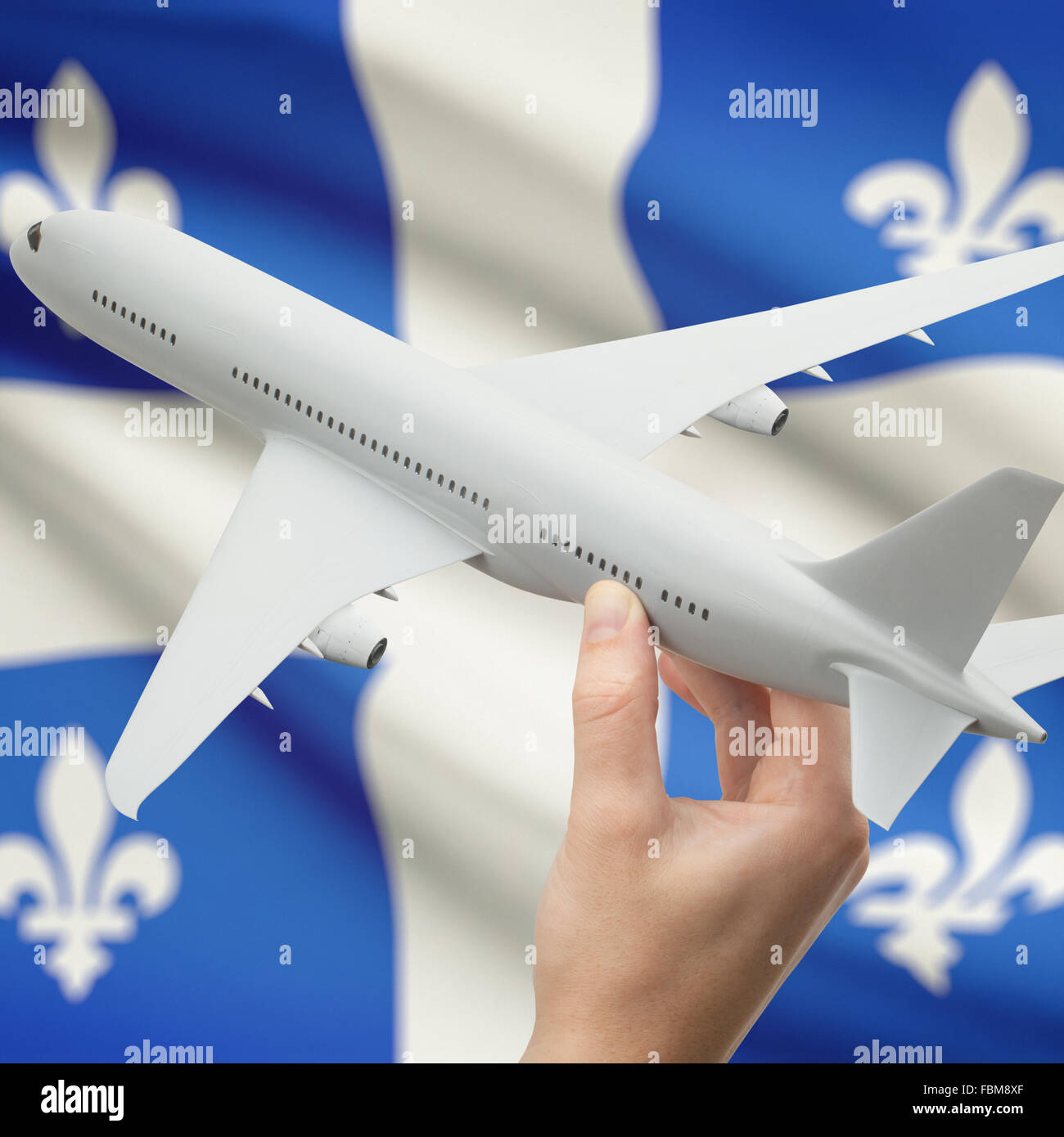 Airplane in hand with Canadian province or territory flag on background series - Quebec Stock Photo
