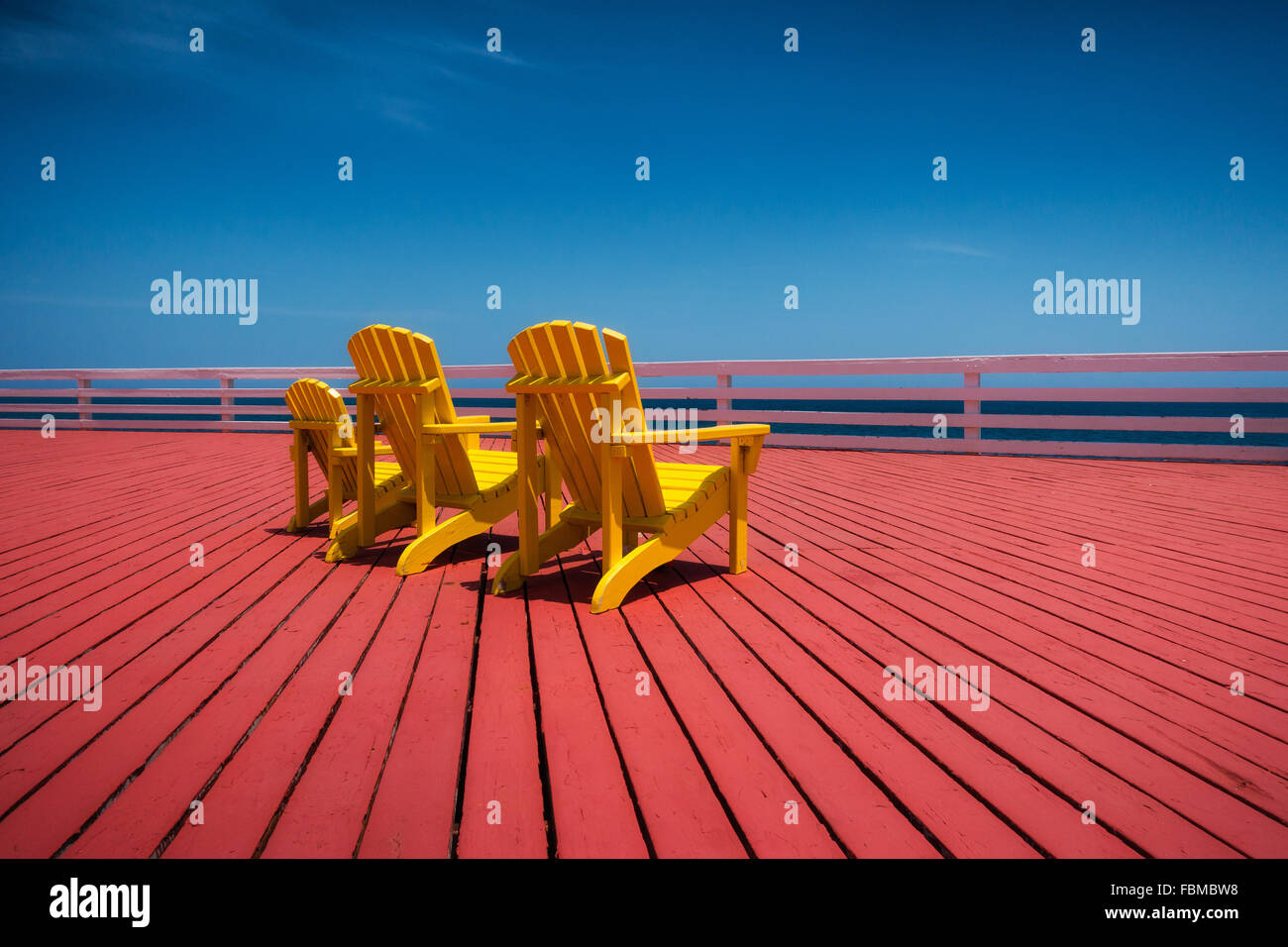 Three yellow chairs on red wooden decking Stock Photo