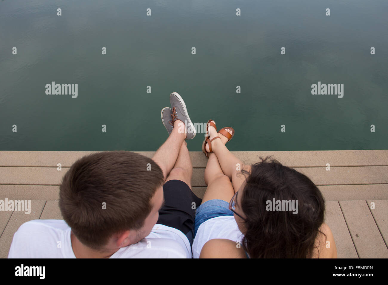 Young Couple sitting by waterfront Stock Photo