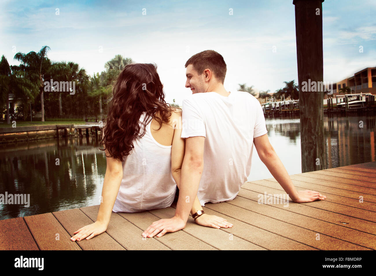Rear view of a couple sitting on jetty Stock Photo