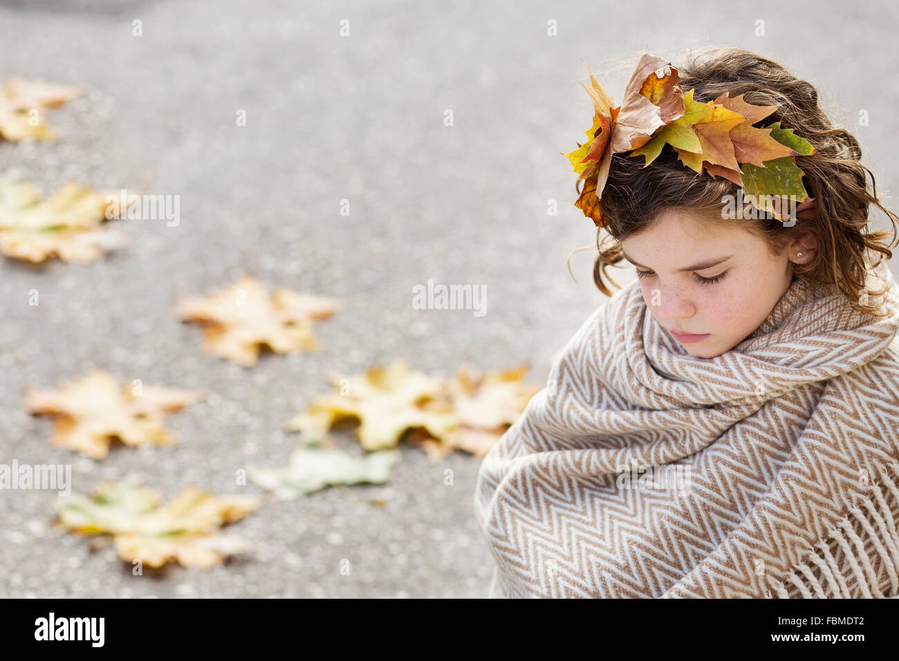 Girl wrapped in a blanket wearing headdress made of autumn leaves Stock Photo