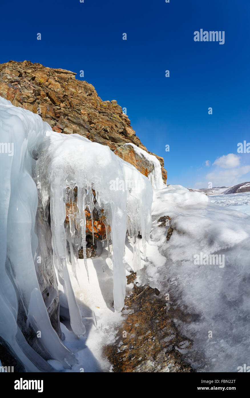 Rocks covered by ice on winter siberian Baikail lake under blue sky backgroun Stock Photo