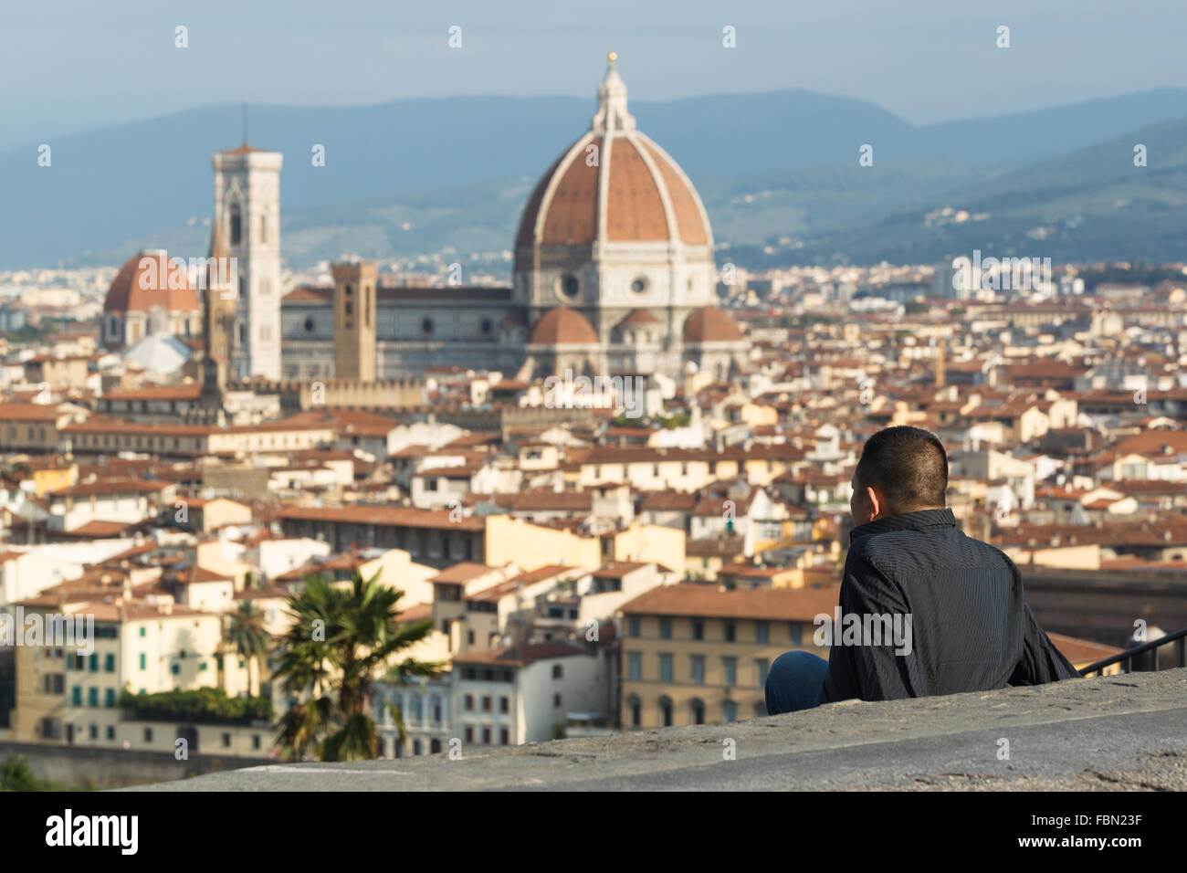 A young man enjoying the view of Santa María del Fiore Cathedral from Piazzale Michelangelo, Florence, Tuscany, Italy. Stock Photo