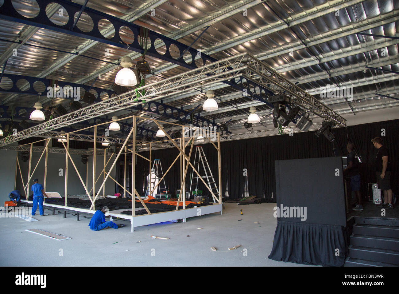 An event's management company building up a stage and runway preparing for a fashion show in a hall Stock Photo